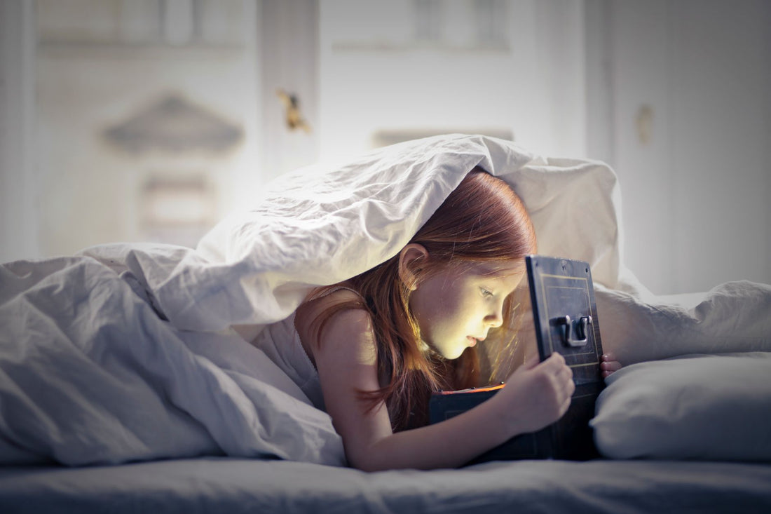 Young child sitting in a cozy bedroom at night with a soft nightlight glowing, looking calm and comforted